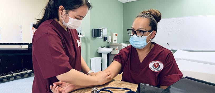 Student practicing drawing blood on another student.