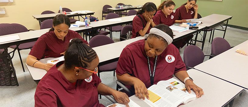 Group of students sitting and reading their textbook in a classroom.