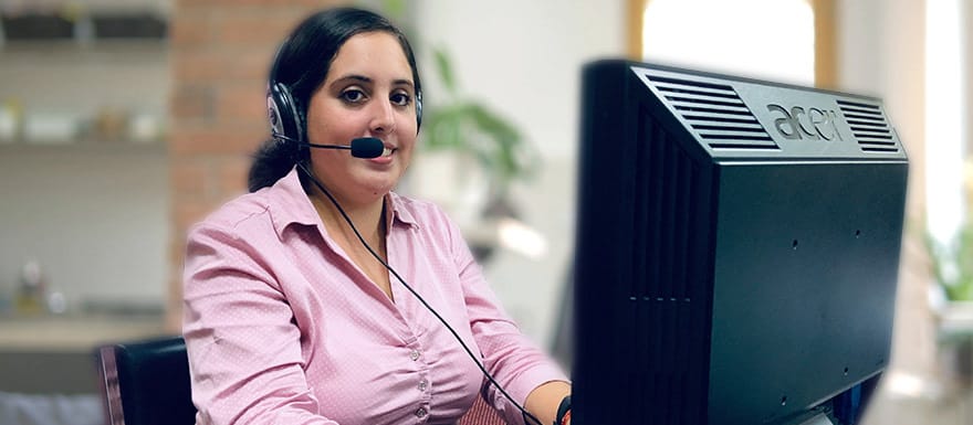 Medical Biller and Coder talking on a headset and using a computer.