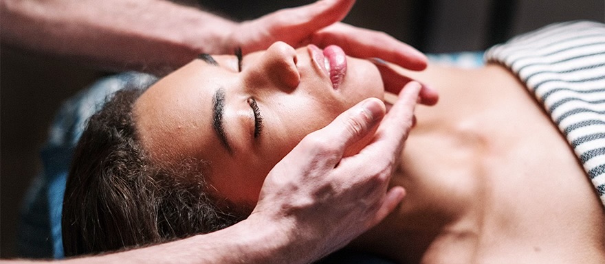 Woman receiving facial massage by a Massage Therapist.